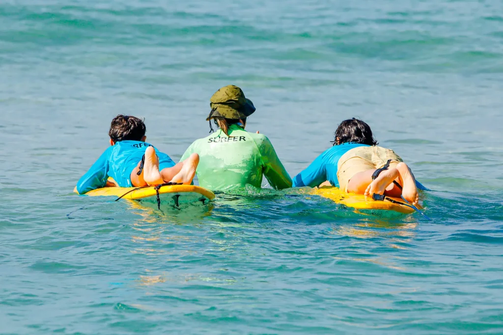 Instrutor do Surf Camp acompanhando as crianças na prancha