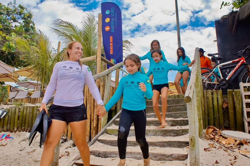 Andrea Lopes descendo para a praia com as alunas do Surf Camp